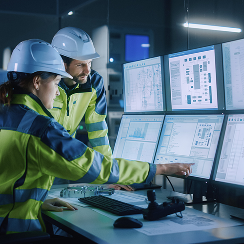 Industry 4.0 Modern Factory: Project Engineer Talks to Female Operator who Controls Facility Production Line, Uses Computer with Screens Showing AI, Machine Learning Enhanced Assembly Process stock photo