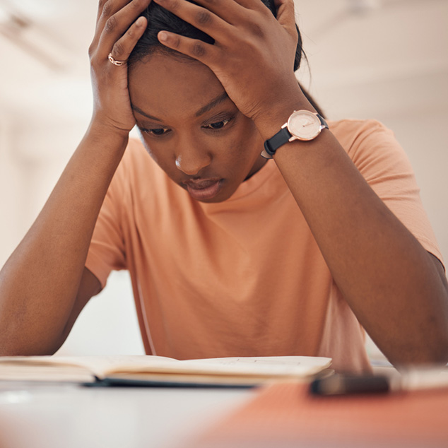 Exam stress, studying and student reading, classroom learning and headache from education. Anxiety, books and African girl with fear of fail on a test, adhd problem and frustrated with school