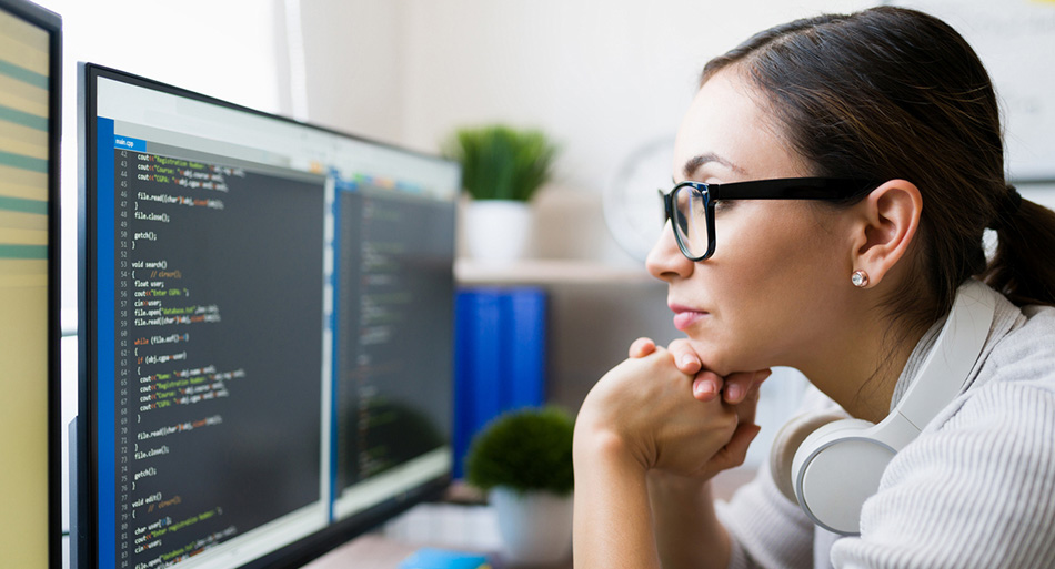 Close up of a smart young woman coding at computer. 